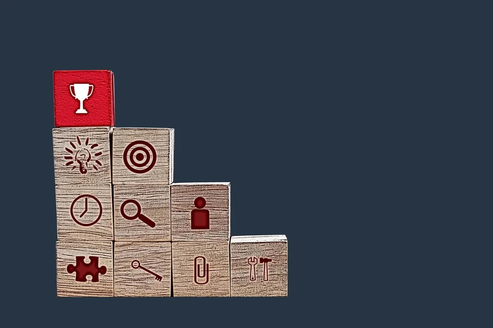 Wooden building blocks with different symbols and red block with a symbol of a trophy on top